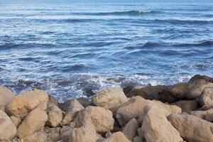 Coastal rocks and waves along the beautiful shores of Spain during a calm day in late afternoon photo