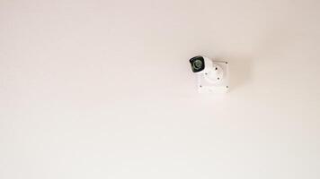 A sleek security camera mounted on a white ceiling, showcasing modern surveillance technology in a minimalist setting. photo