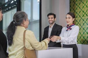 airline officers return passport to passenger that standing in queue,ground attendants working at airport check-in area,airlines service photo