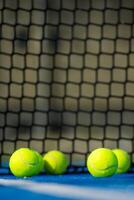Selective focus. Net of a blue paddle tennis court and four balls near the white line. Selective focus. photo