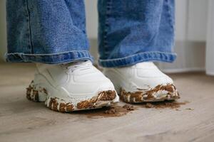 child walks around the house in dirty shoes. Concept of child soiled laminate flooring. photo