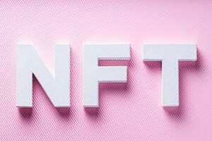NFT White Letters on Pink Diagonal Striped Background, Crypto Art Concept, Top View photo