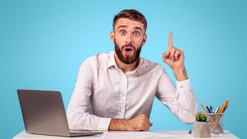 Millennial company worker with speech bubble above his head having creative idea at office, blue studio background, mockup for design. Young businessman with word cloud finding solution to problem photo