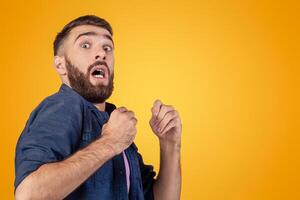 Young hipster guy being scared or terrified over grey studio background. Millennial man suffering from fear or shock, having panic attack. Negative human emotions and feelings concept photo