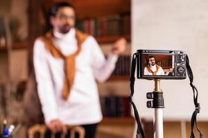 Teacher Blogger Guy Making Lesson For Educational Blog Standing Near Blackboard Indoor, Focus On Camera. E-Teaching And Online Learning, Knowledge And Modern Distance Education. Shallow Depth photo