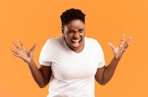 Angry Plus-Size African American Lady Shouting Freaking Out Standing Posing Over Yellow Studio Background, Looking At Camera Angrily. Negative Emotion, Madness And Anger Concept photo
