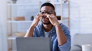 Glaucoma. African American Man Massaging Tired Eyes Suffering From Eyestrain And Fatigue, Exhausted After Work On Computer Sitting At Workplace In Office. Eye Sight Problem Concept photo