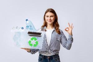 Beautiful Young Lady Holding Container With Empty Plastic Bottles And Showing Ok Gesture, Millennial Eco-Activist Woman Enjoying Sorting Garbage For Recycling, Standing On Light Background photo