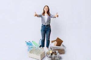 Materials Recycling Concept. Happy Young Woman Standing Next To Containers With Different Waste And Showing Thumbs Up At Camera, Millennial Eco-Activist Woman Recommending Garbage Sorting System photo