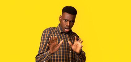 Oh No. Disgusted African American Guy Showing Refuse Gesture With Hands, Frightened Black Man Keeping Away Of Something, Expressing Negative Emotions Over Yellow Studio Background, Copy Space photo