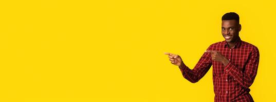 Check This. Positive Black Millennial Guy Pointing Aside At Copy Space On Yellow Background With Both Hands, African American Man Demonstrating Free Place For Your Design Or Advertisement, Panorama photo