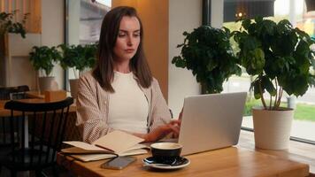Caucasian business woman laptop working remote writing notes sitting in cafe chatting with clients internet female freelancer girl at cafeteria table work online write ideas in notebook study distant video
