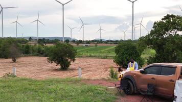 An engineer father and his daughter more work in front of a car before getting off work in a wind turbine field,4 video