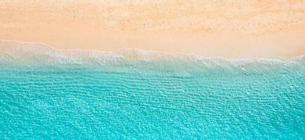 Drone shot top view sandy shoreline meeting calm blue ocean, natural textures and soft wave patterns, relaxing tropical seascape ideal for vacation imagery, beach backgrounds, peaceful design visuals photo