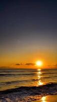 A sunset over the ocean with waves and a beach video