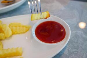 Delicious crinkle fries dipped in ketchup casual dining experience restaurant table close-up view photo