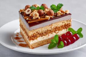 Delicious layered cake with caramel, hazelnuts and chocolate icing, decorated with fresh mint and red currant photo