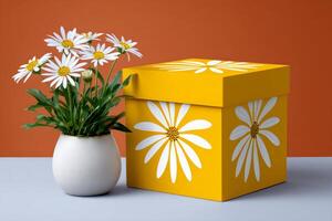 Yellow gift box with white daisy pattern and real daisies in a vase photo