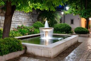 Illuminated fountain sprinkling water in a peaceful courtyard at night photo