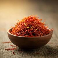 A bowl filled with vibrant saffron threads on a wooden surface. photo