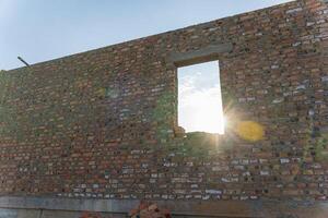 Morning light shines through an open window in a brick wall at a construction site, highlighting ongoing building work and materials photo