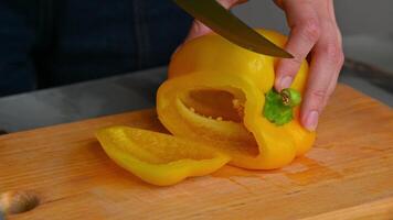 Bright yellow bell pepper, demonstration of texture and color of pepper, female hand cutting vegetables on wooden board on dining table, food preparation video