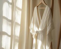 A white robe hanging on a clothes rack photo