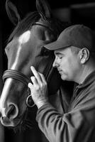 A man is touching the nose of a horse photo