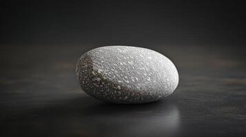 Smooth grey stone on dark surface photo