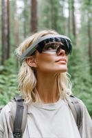 Blonde hiker wearing smart glasses exploring forest using augmented reality technology photo