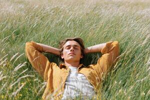 Young man relaxing lying in a field of tall grass photo