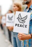 Group of individuals holding signs with a dove symbol and the word peace, demonstrating unity and hope during a peaceful protest in an urban setting photo