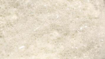 Creamy ASMR soap foam bubbles moving gently on neutral background video