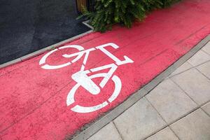 Bicycle lane marked with bright red paint beside walkway in a city area photo
