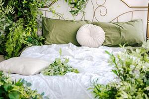 Cozy bed adorned with greenery and soft linens creating a serene atmosphere in a bedroom photo