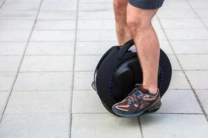 Rider enjoys using a one-wheeled device on a city sidewalk, riding a unicycle photo
