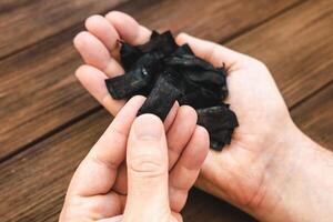 Handful of black Nicotine snus pads displayed on wooden table in natural light photo