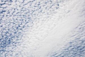 Fluffy clouds create a textured sky over a tranquil landscape during the late afternoon hours photo