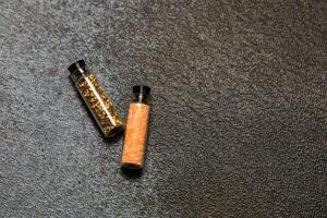 Two small spice jars on a dark textured surface showcasing colorful seasonings photo