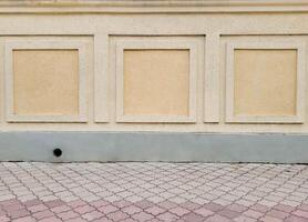 A wall with decorative beige bark beetle plaster and part of the paving slabs. photo