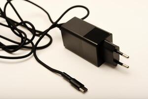 Black fast-charging adapter on white. A new charger for gadgets with a wire. USB charging with a wire. photo