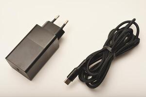 Compact black power adapter on white. A new charger for gadgets with a wire. USB charging with a wire. photo