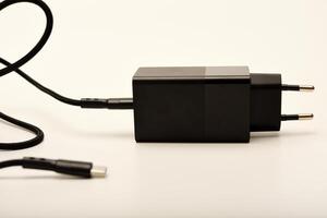 Minimalist black power adapter on white. A new charger for gadgets with a wire. USB charging with a wire. photo
