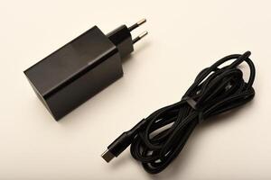 Modern black USB charger isolated on white, A new charger for gadgets with a wire. USB charging with a wire. photo