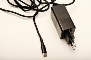 Black charger on white background. A new charger for gadgets with a wire. USB charging with a wire. photo