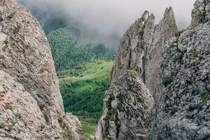 Rocky mountain ridge and cliffs rising above clouds on a moody summer day. Bolshoy Tkhach national park photo