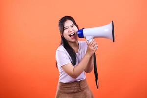 Enthusiastic woman using megaphone with an orange background announcing news photo