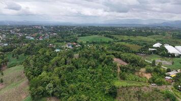 Drone footage capturing a rainy landscape where mountains fade into mist and the plains below stay vivid green. A mood of peaceful isolation fills the scene. video