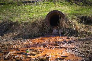 Rusty Drain Pipe Releasing Polluted Water Into Contaminated Soil in a Rural Outdoor Environment photo