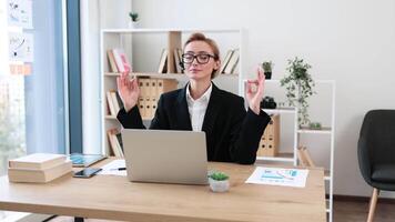 Blond businesswoman wearing glasses meditating at desk in office workplace during work break, promoting relaxation and mindfulness during busy professional environment. video